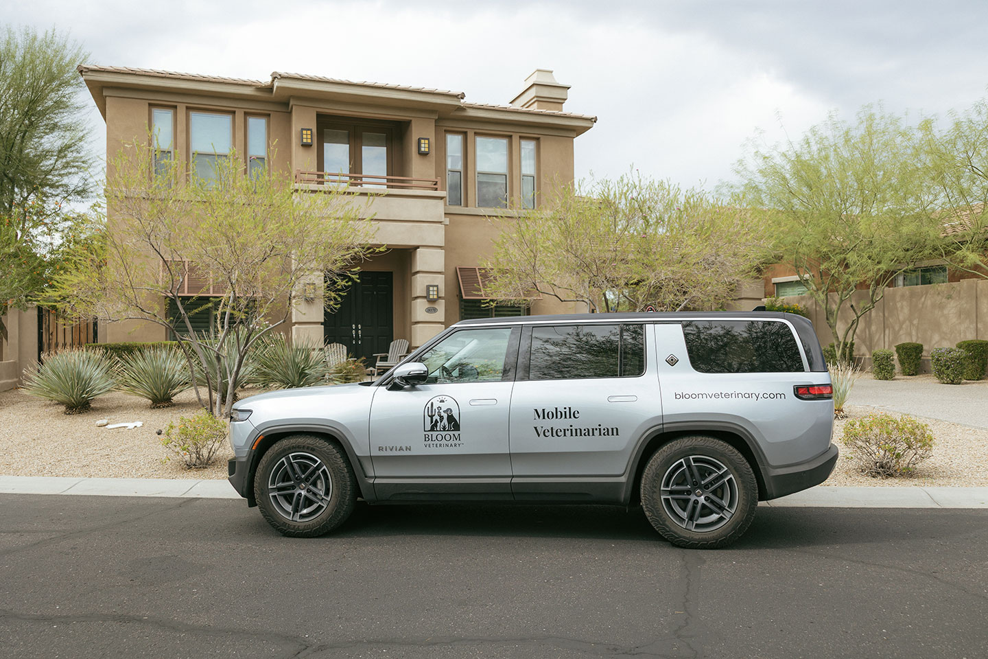 A Bloom Veterinary branded mobile clinic parked in front of a home.